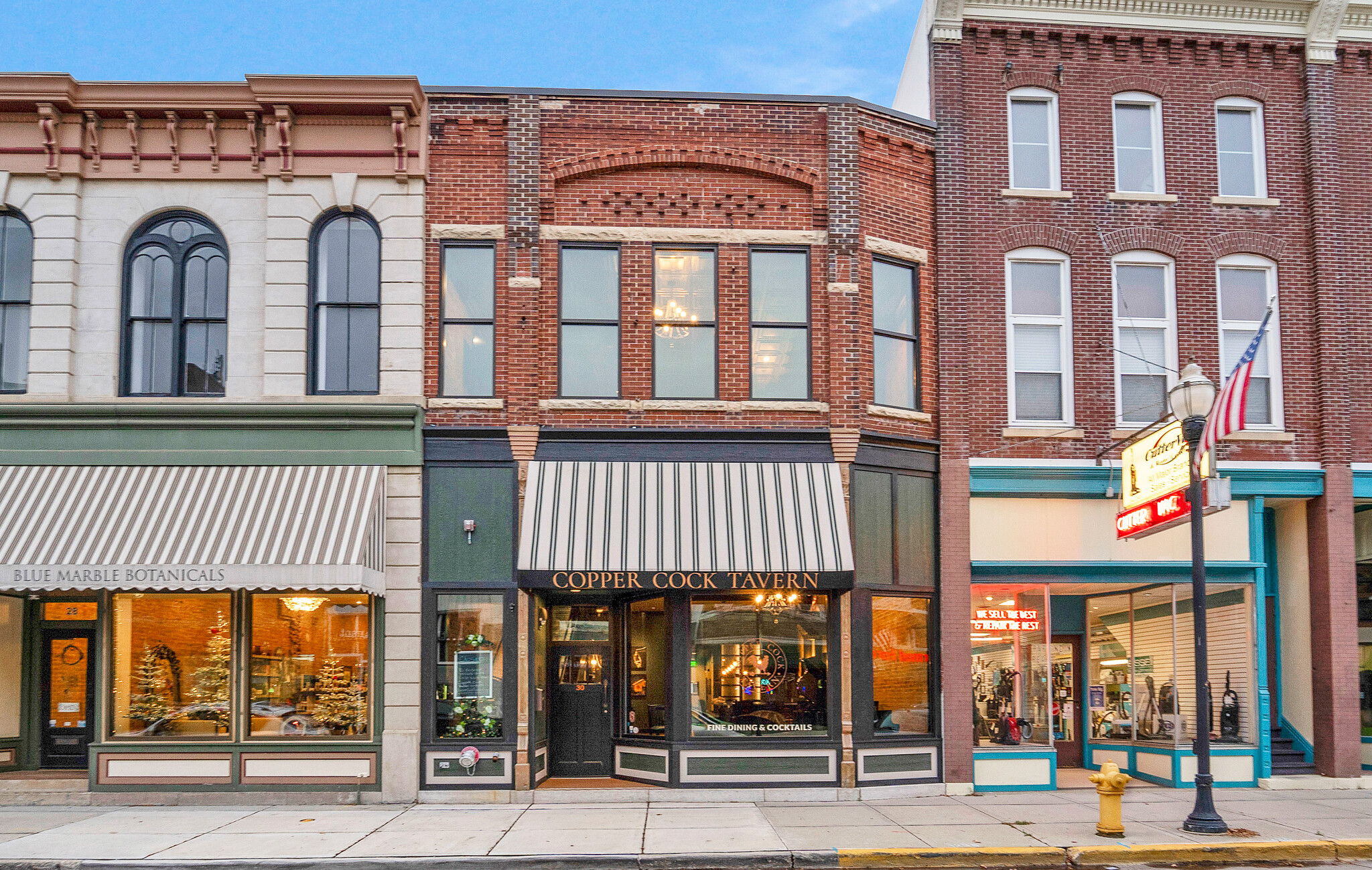 Charming street scene with distinctive storefronts, brick and painted facades, evoking nostalgia and warmth in a lively atmosphere.