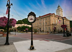 Charming town square with a historic building, decorative clock, flowers, and a pastel sky evokes nostalgia and tranquility.