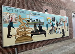 Vibrant mural at Swope Art Museum shows figures engaging with art, evoking inspiration, joy, and appreciation for creativity.
