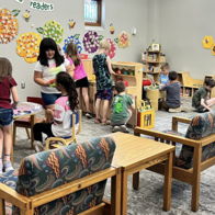 Engaged children playing with toys in a colorful classroom, overseen by a nurturing adult, radiating joy and curiosity.