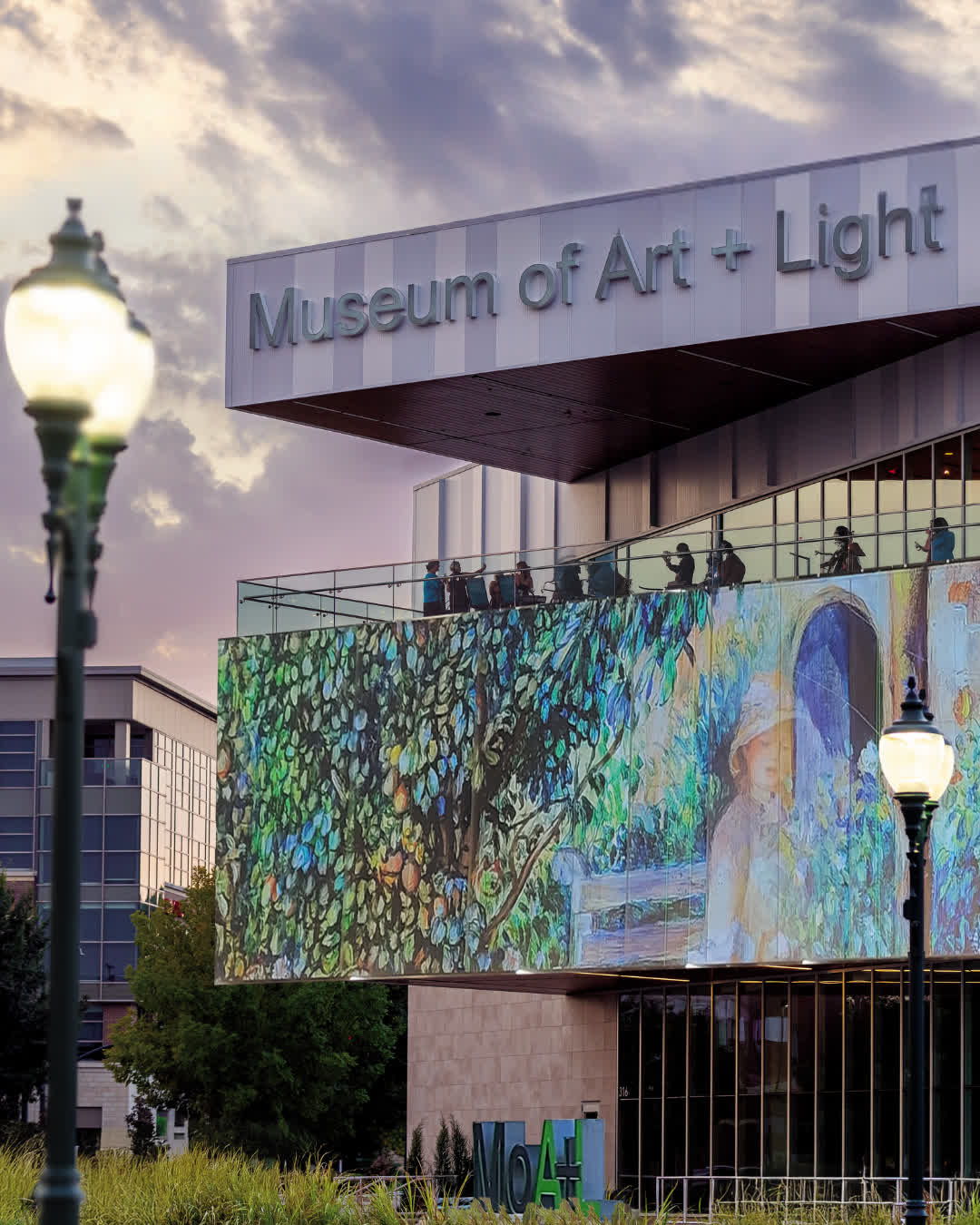 Vibrant evening view of the Museum of Art + Light showcasing colorful digital artwork, evoking community and creativity.