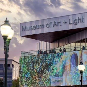 Vibrant evening view of the Museum of Art + Light showcasing colorful digital artwork, evoking community and creativity.