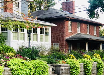 Charming scene of two homes with a vibrant garden, evoking warmth and nostalgia in a peaceful, inviting setting.