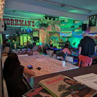 Lively interior of "Workman's" bar, vibrant lighting, patrons socializing, evoking relaxation and enjoyment in a festive atmosphere.