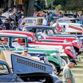 A vibrant car show features vintage cars and a diverse crowd enjoying the nostalgic atmosphere and celebrating automotive history.