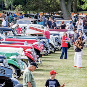 A vibrant car show features vintage cars and a diverse crowd enjoying the nostalgic atmosphere and celebrating automotive history.
