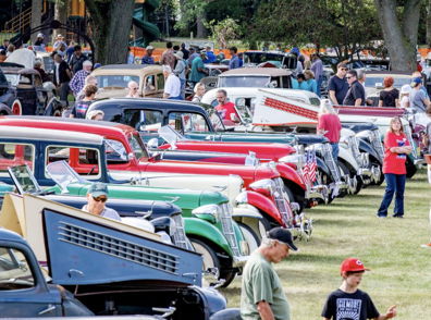 A vibrant car show features vintage cars and a diverse crowd enjoying the nostalgic atmosphere and celebrating automotive history.