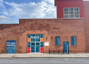 A colorful brick building entrance with inspirational phrases invites creativity and community, showcasing artful signage.