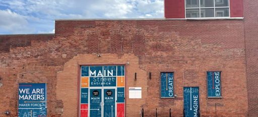 A colorful brick building entrance with inspirational phrases invites creativity and community, showcasing artful signage.