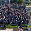 A large group in blue attire gathers outdoors, showcasing unity, pride, and professionalism in a celebratory atmosphere.