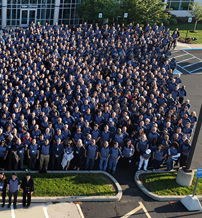 A large group in blue attire gathers outdoors, showcasing unity, pride, and professionalism in a celebratory atmosphere.