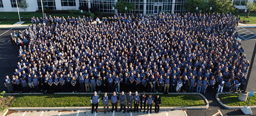 A large group in blue attire gathers outdoors, showcasing unity, pride, and professionalism in a celebratory atmosphere.