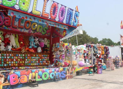 A vibrant carnival scene with colorful balloon and plush toy stalls, evoking nostalgia and joyful excitement.