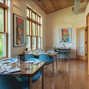 A bright dining area with wooden elements, large windows, and vibrant decor, creating a warm, inviting atmosphere.