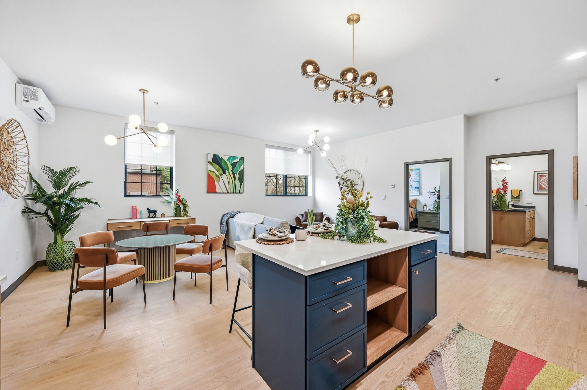 Modern, cozy living area with stylish dining set, natural light, greenery, and contemporary art, inviting warmth and sociability.