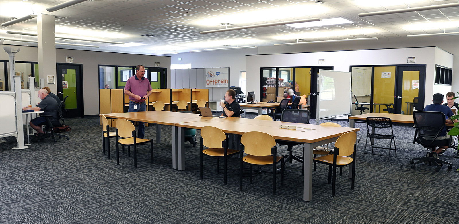 Modern open workspace with tables, laptops, and people collaborating, creating a community-focused, productive atmosphere.