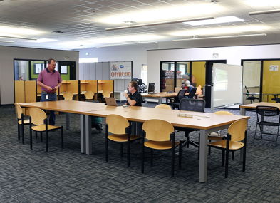 Modern open workspace with tables, laptops, and people collaborating, creating a community-focused, productive atmosphere.