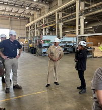 Group of individuals in safety helmets discussing in a spacious factory, highlighting professionalism, teamwork, and safety.
