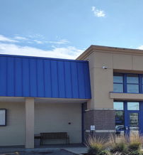 Modern health center with blue metal roof, large windows, welcoming atmosphere, and "Konza Prairie Community Health Center" sign.