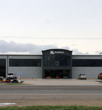 A modern building, likely a dealership, features large windows, vehicles on display, and an open area, evoking professionalism.