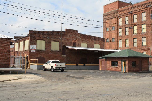Gritty urban scene with brick buildings, a parked white truck, evoking nostalgia and reflecting on industrial history.