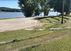 A tranquil riverside scene with grassy slopes, trees, and calm water, evoking relaxation and connection to nature.