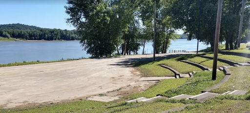 A tranquil riverside scene with grassy slopes, trees, and calm water, evoking relaxation and connection to nature.
