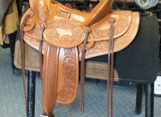 An intricately crafted leather saddle on a stand, surrounded by equestrian gear, evokes nostalgia and artisanal appreciation.