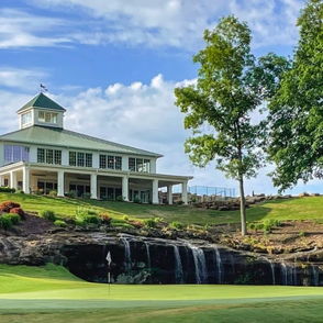 A serene golf course with lush grass, a charming clubhouse, tall trees, and a small waterfall under a clear blue sky.