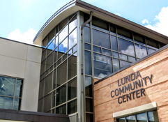 Modern Lunda Community Center features stone and glass architecture, reflecting sky and inviting community spirit.
