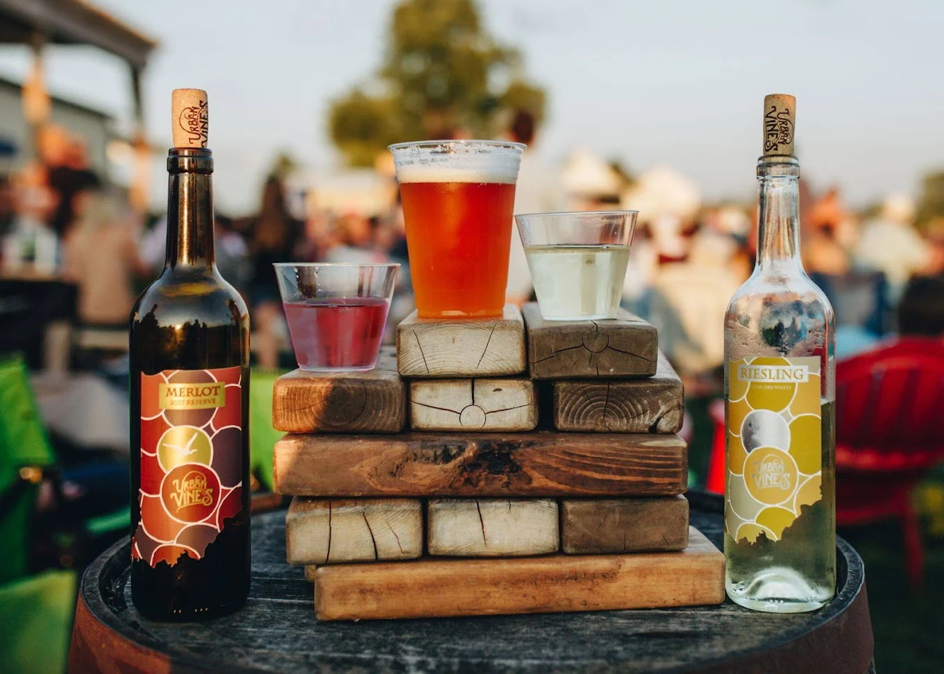 Cheerful outdoor gathering with wine, colorful drinks, and beer on wooden blocks, evoking relaxation and camaraderie.