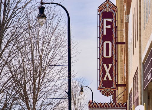 Vintage theater marquee reading "FOX" in a charming small-town setting, evoking nostalgia and community warmth.