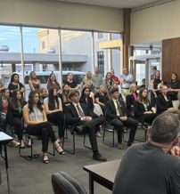 Formal gathering with speakers at a podium and an attentive audience, conveying seriousness and community engagement.