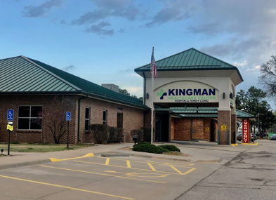Brick building with a green metal roof, flag, and organized parking, evoking calmness, community, and reliability.