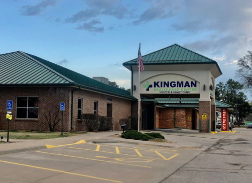 Brick building with a green metal roof, flag, and organized parking, evoking calmness, community, and reliability.
