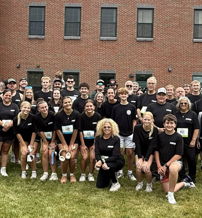 Group of people in matching black shirts outdoors, holding awards; a celebration of teamwork and community spirit.