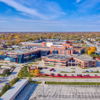Vibrant autumn campus with modern brick and glass buildings, surrounded by colorful trees, evoking tranquility and warmth.