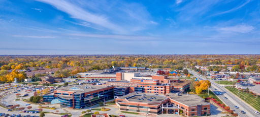 Vibrant autumn campus with modern brick and glass buildings, surrounded by colorful trees, evoking tranquility and warmth.