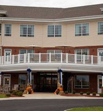 A inviting residential building with beige and brick red facades, large windows, and a welcoming lawn encourages community and comfort.