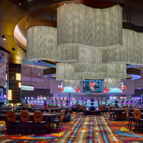 Vibrant casino interior with stylish lighting, colorful carpet, slot machines, and a lively social atmosphere evoking excitement.