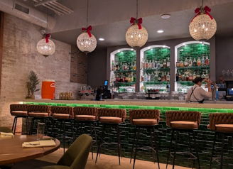 Modern bar with sleek design, warm lighting, inviting seating, and festive touches, creating a cozy social atmosphere.