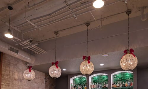 Modern bar with sleek design, warm lighting, inviting seating, and festive touches, creating a cozy social atmosphere.