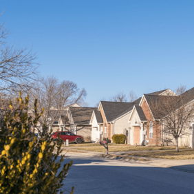 Quiet suburban neighborhood with well-maintained homes, clear sky, and greenery, evoking tranquility and community comfort.