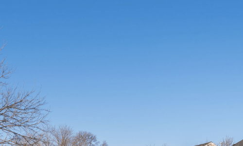Quiet suburban neighborhood with well-maintained homes, clear sky, and greenery, evoking tranquility and community comfort.