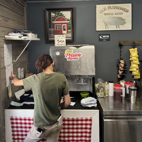 Cozy food counter with a worker, checkered tablecloth, snacks, and a warm, inviting atmosphere for casual dining.