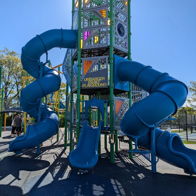 Colorful playground with twisting blue slides, tall towers, and sunny skies evokes joy and playful exploration.
