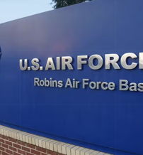 Sign for Robins Air Force Base with a blue background, silver lettering, and Air Force emblem, evoking pride and respect.