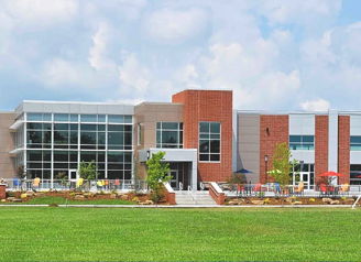Modern community center with glass windows, colorful chairs, and a lawn, exuding a welcoming and tranquil atmosphere.