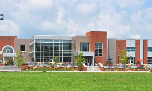 Modern community center with glass windows, colorful chairs, and a lawn, exuding a welcoming and tranquil atmosphere.