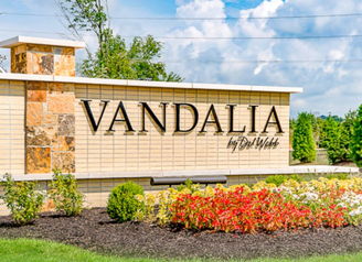 Welcoming "Vandalia" sign amid lush greenery and flowers, evoking warmth, positivity, and community pride.